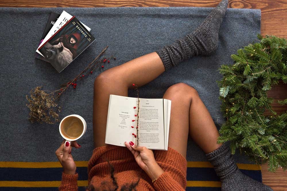 fotografía en picado de una chica con un café y un libro